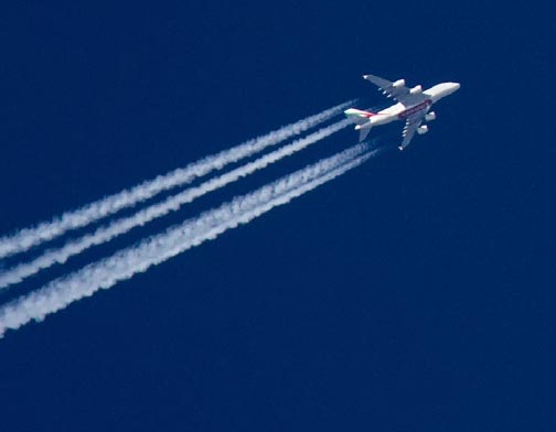 Airplane flying in a blue sky, while leaving a white trail